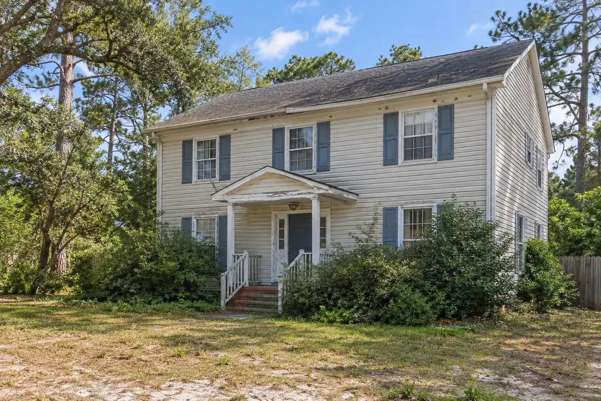 A house with peeling paint and worn roof shingles that needs repairs